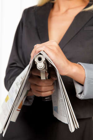 Woman with a weapon hidden under a newspaperの写真素材