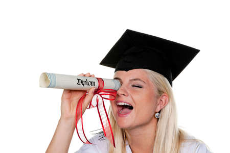 Playful young woman with graduation cap looks through her rolled-up diploma. Horizontal.の写真素材