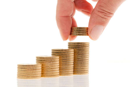 Close-up of a hand placing coins on top of a stack. Horizontal.の写真素材