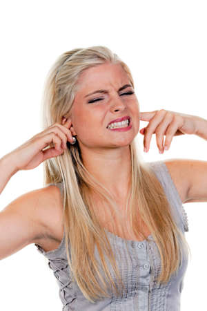 A young woman plugging her ears and grimacing. Vertically framed shot.の写真素材