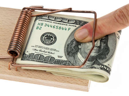Someone's finger and a wad of US currency caught in a mousetrap. Horizontally framed shot.の写真素材