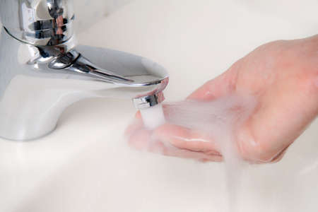 Cropped close-up of hand with running water and soap. Horizontally framed shot.の写真素材