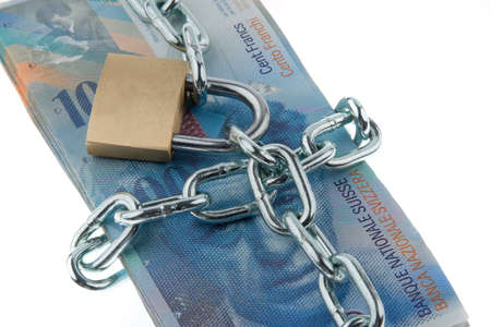 Swiss currency with chain and lock. Horizontally framed shot.