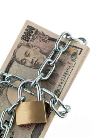 Japanese currency with chain and lock. Vertically framed shot.の写真素材