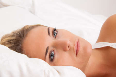 A young woman lies awake in bed. Sleepless and thoughtful.の写真素材