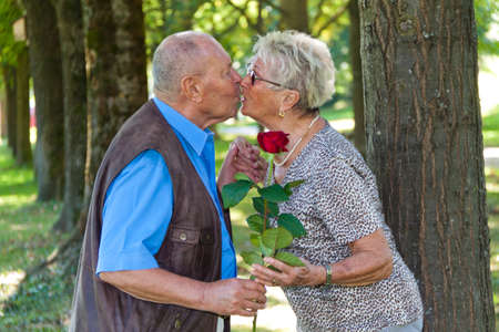 Mature senior couple is in love. Man hands over a rose.の写真素材