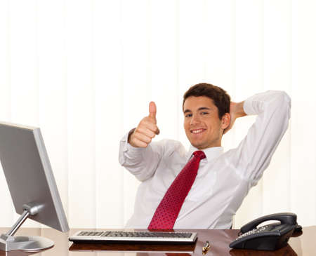 A successful young manager sitting at a desk and smiles.の写真素材