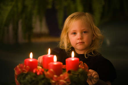 Child with Advent wreath for Christmas. 4 candles lit.の写真素材
