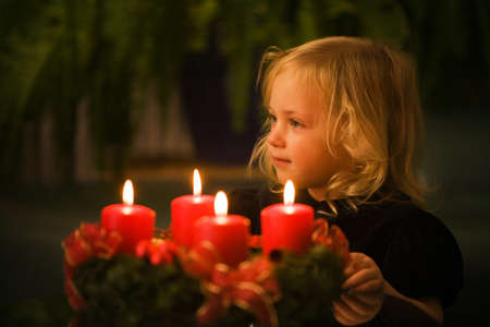 Child with Advent wreath for Christmas. 4 candles lit.の写真素材