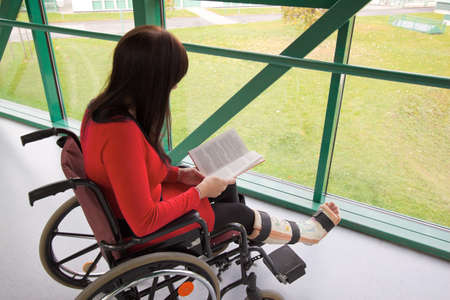 Young woman with a leg cast and wheelchair in the hospitalの写真素材