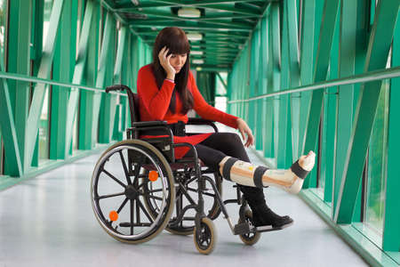 Young woman with a leg cast and wheelchair in the hospitalの写真素材