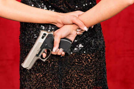 Woman in the little black dress posing with a gunの写真素材