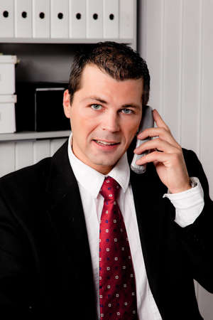 A young businessman in the office with phoneの写真素材