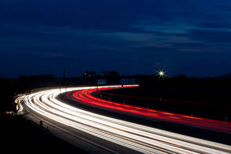 Cars at night on a highway. Rope lights and illuminated signs