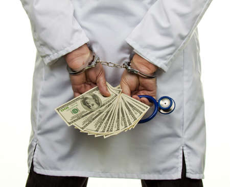 A doctor with dollar bank notes and handcuffsの写真素材