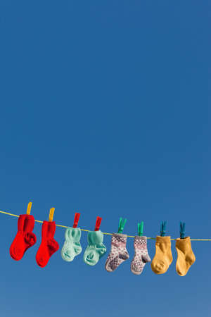 Baby socks on clothesline to dry. Blue sky.の写真素材