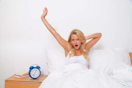 Young pretty woman getting up and waking up. Good mood in the morning in bedの写真素材