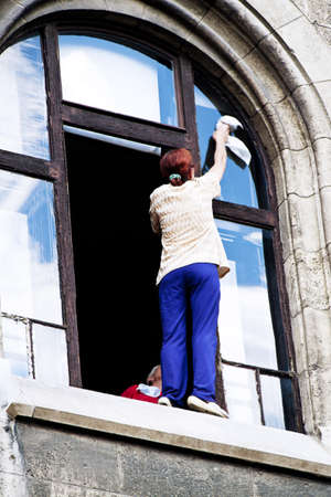 A woman washing windows. Danger when cleaning the house.の写真素材