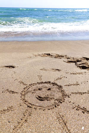 On a sandy beach, a sun drawn in the sandの写真素材