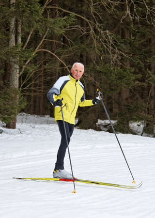 senior in winter on snow to cross country skiing with skisの写真素材