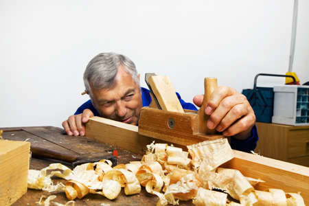 a carpenter with a planer and wood shavings in the workshop.の写真素材