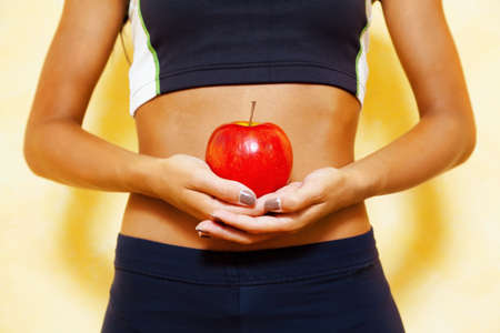 a slender young woman receives an apple in his hand. fit through healthy dietの写真素材