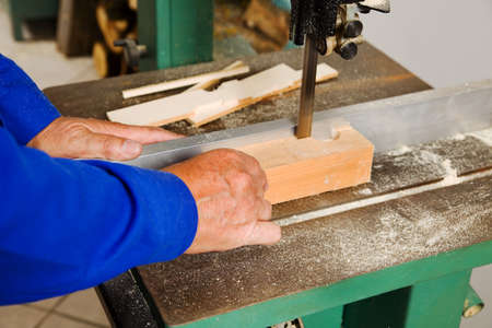 an elderly carpenter on a band saw in a carpentry shopの写真素材