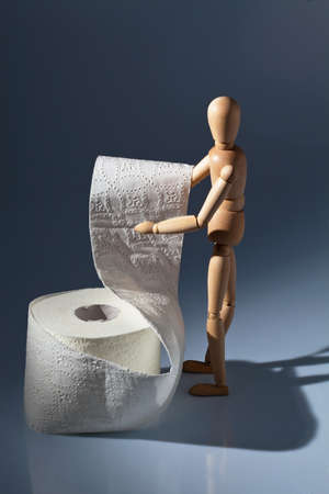 a wooden figure and a roll of toilet paper.の写真素材