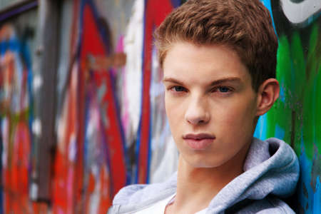 a cool-looking young man in front of graffitiの写真素材