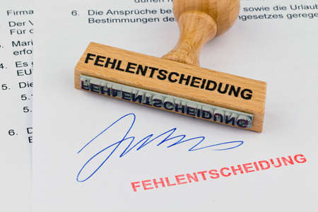 a stamp made of wood lying on a document. saying the wrong decisionの写真素材