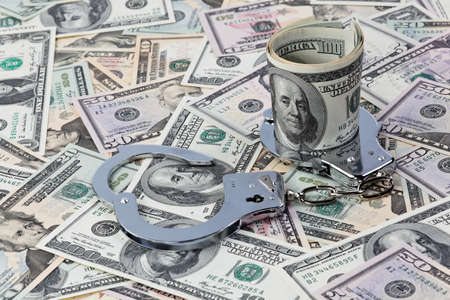 dollar currency notes and handcuffs as a symbol of economic crimeの写真素材