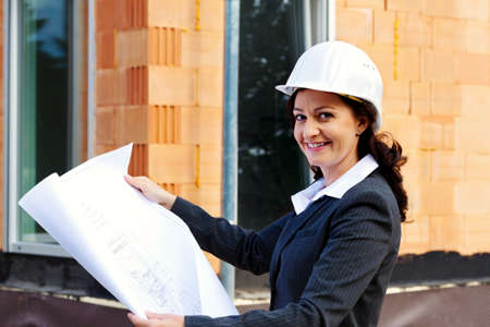 architect with blueprint before shell of a house building a house.の写真素材