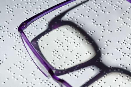 a pair of glasses and a book in braille  read with disabilities の写真素材