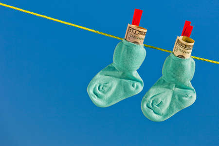baby socks on clothesline with dollar bills  blue sky の写真素材