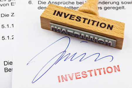 a stamp made of wood lying on a document  german inscription  investmentの写真素材