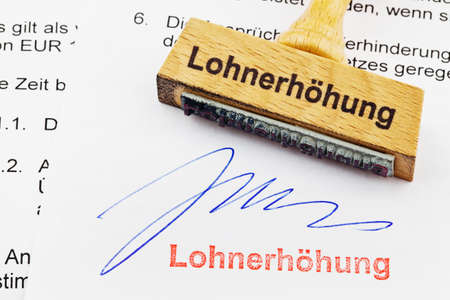 a stamp made of wood lying on a document  german inscription  wage increaseの写真素材