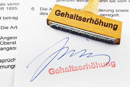 a stamp made of wood lying on a document  german inscription  raiseの写真素材