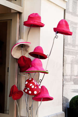 several red hats are waiting for buyers in front of a millineryの写真素材