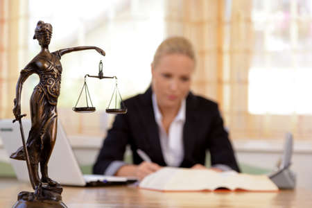 a young lawyer is sitting at her desk in the officeの写真素材