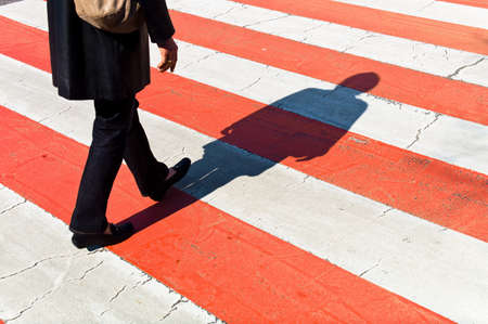 a woman walks on a pedestrian crossing  shadows on a protection path の写真素材