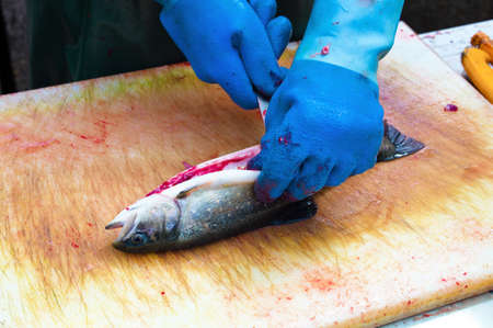 a fish in a fish market is filleted by fishermenの写真素材