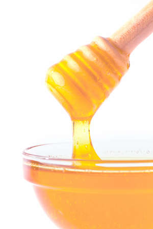 a spoon is kept in a pot of honey. isolated against white backgroundの写真素材