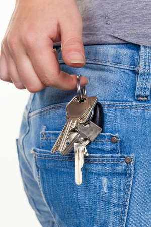 the hand of a young woman in jeans with keyring  key for car and homeの写真素材