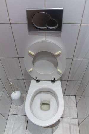 a toilet in an apartment  with an open toilet seat