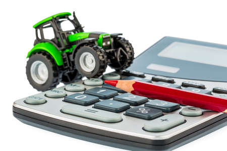 a tractor and a red pen on a calculator  costs of fuel, insurance and wear  costs and subsidies in agricultureの写真素材