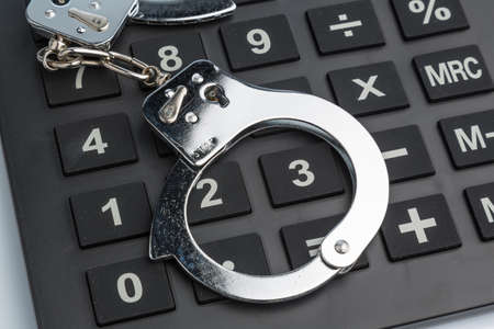 calculators and handcuffs on a white background  representative photo of white-collar crime