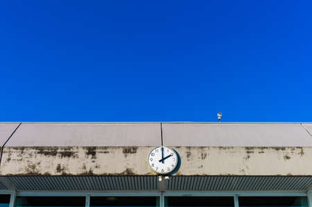 a clock and a video camera in front of blue skyの写真素材