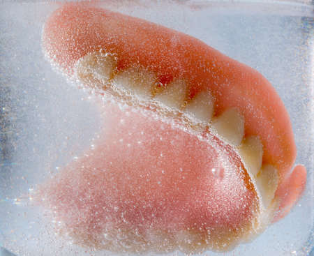 a denture is cleaned in a glass with water  proper hygiene の写真素材