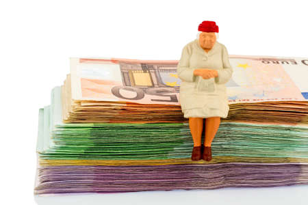 figure of an old woman sitting on a stack of bills, symbolic for pension and retirementの写真素材