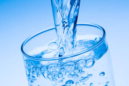 pour water into a glass, symbolic photo for drinking water, excess and waste pour water into a glass, symbolic photo for drinking water, excess and waste